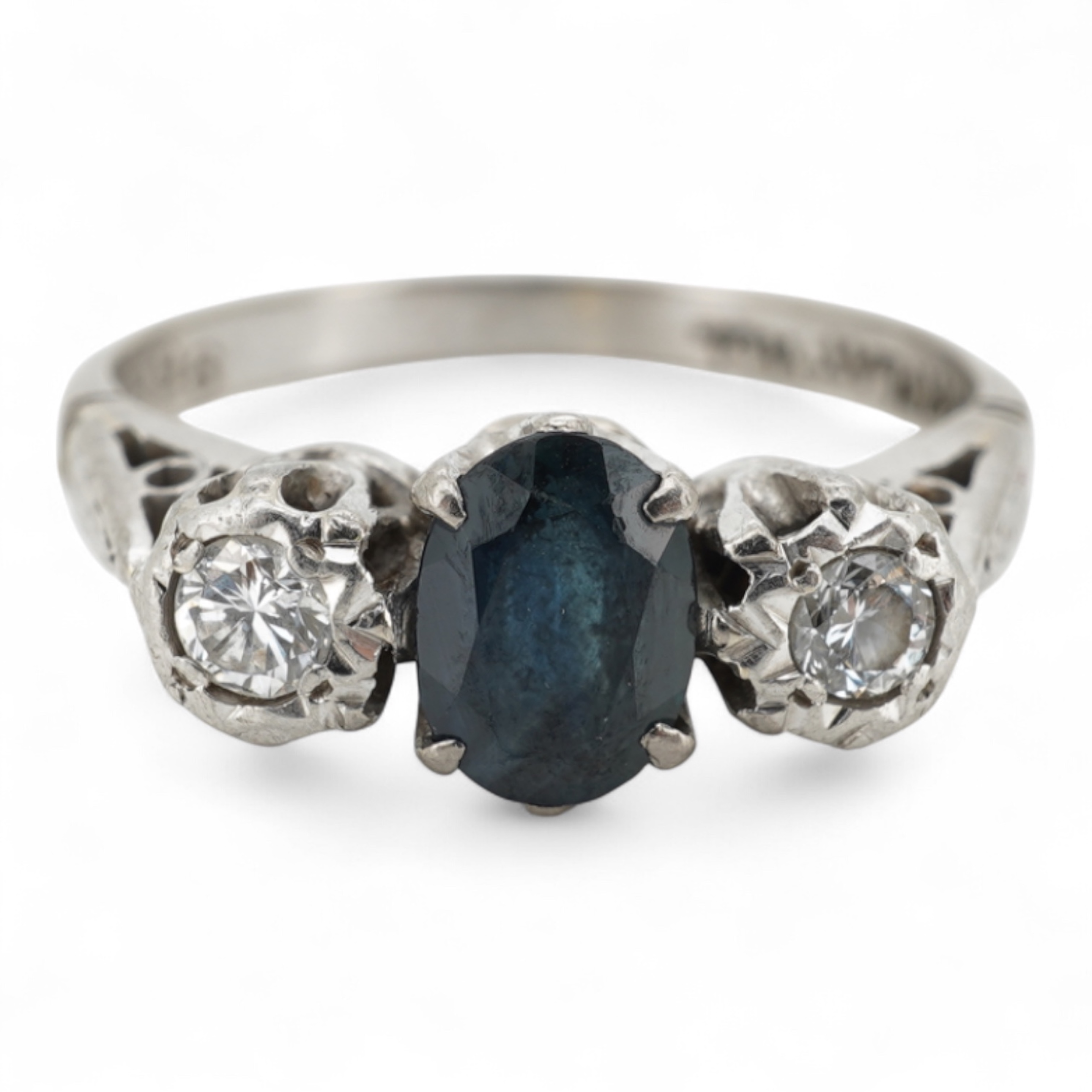 A sapphire and diamond ring, claw-set with an oval sapphire measuring approximately 6.2 x 4.5 x 3.2mm, between shoulders set with brilliant-cut diamonds totalling approximately 0.14 carats, mounted in platinum and pallad